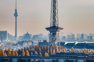 Communications tower in city against sky