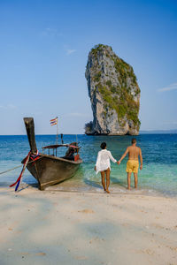 Full length of couple embracing on beach against sky