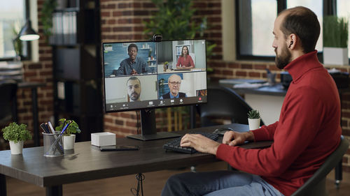 Young businessman on video call with colleague through desktop pc