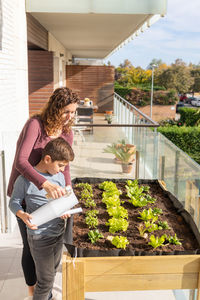 Mother and son watering vegetables in their urban garden