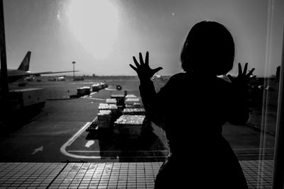 silhouette girl looking through window at airport