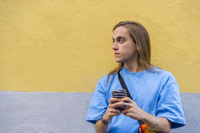 Man using mobile phone while wearing a belt bag with the lgbt rainbow flag.