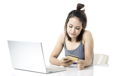 Young woman using phone while sitting on laptop