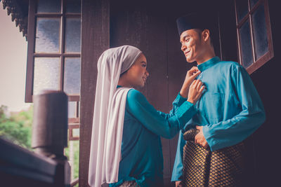 Young couple standing against window