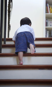 Low angle view of baby boy crawling on steps at home