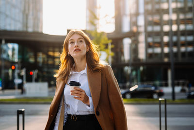 Portrait of young woman standing in city