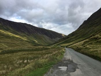 Road leading towards mountains against sky