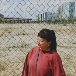 Woman standing against chainlink fence