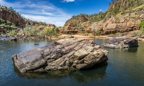 Rocks in katherine river by mountains against sky