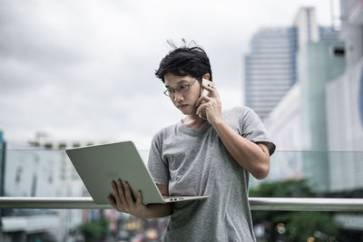 Young man using mobile phone in city