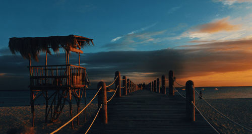 Pier amidst sea against sky during sunset