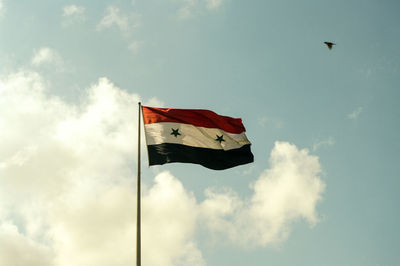 Low angle view of flag flying against sky