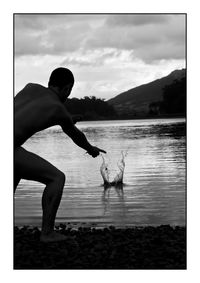 Side view of young woman with dog on lake against sky