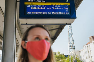 Close-up of woman wearing mask standing at railroad station