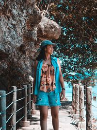 Woman walking on footbridge against tree