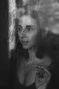 Close-up portrait of woman seen through glass window