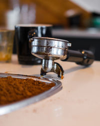 Close-up of coffee and porta filter on table in kitchen