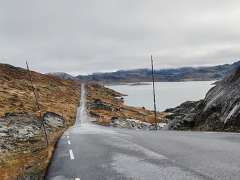 Road leading towards mountains against sky