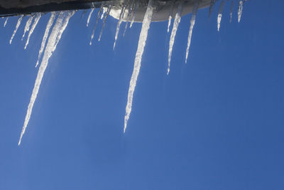 Low angle view of icicles against blue sky