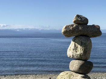 Stack of stones on beach against sky