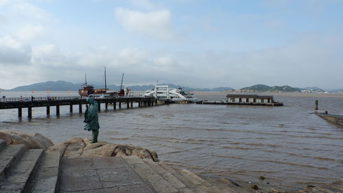 Man standing on pier over sea against sky