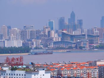 Buildings by river against sky in city