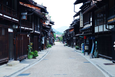 Empty road amidst buildings in city