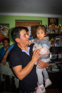 Full length of father and daughter standing against building