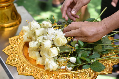 Cropped hands picking roses in tray