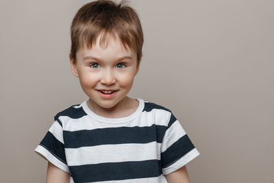 Portrait of smiling boy against gray background