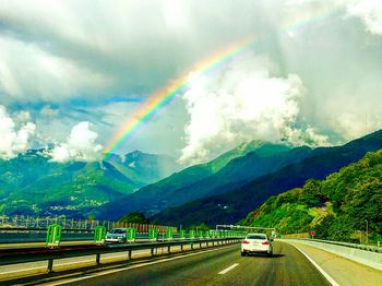 Road leading towards mountains against cloudy sky