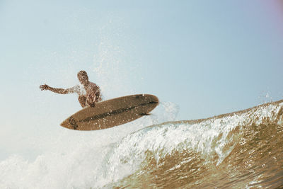 Man surfing in sea against sky