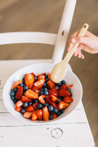 High angle view of hand holding strawberries on table