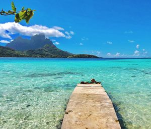 Scenic view of sea and mountains against blue sky