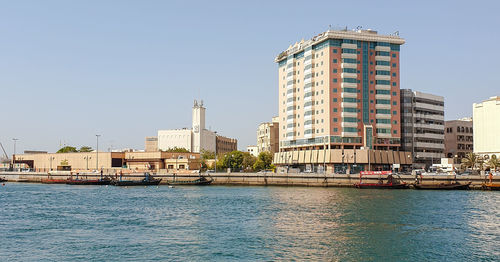 Sea by buildings against sky in city