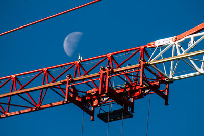 Low angle view of crane against clear blue sky