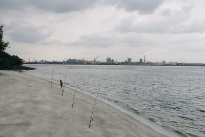 People on beach in city against sky