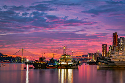 Illuminated bridge over river at sunset