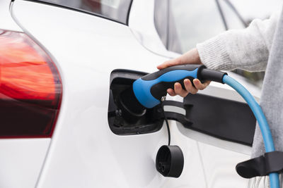 Woman plugging charger in electric car at station