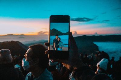 People photographing against sky during sunset