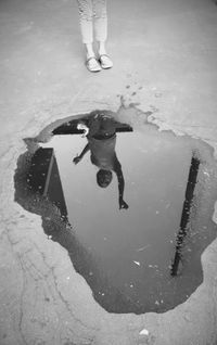 Low section of man standing in puddle