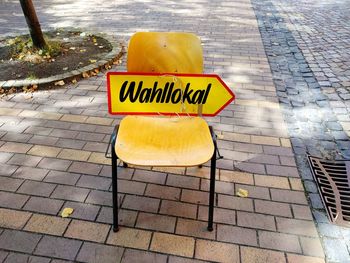 High angle view of chair with text on sidewalk