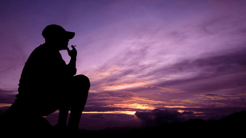 Silhouette man photographing against sky during sunset