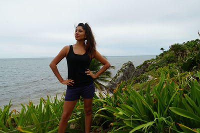 Young woman standing by sea against sky