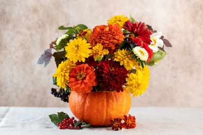 A beautiful autumn bouquet of yellow and red flowers in a pumpkin. the concept of autumn,