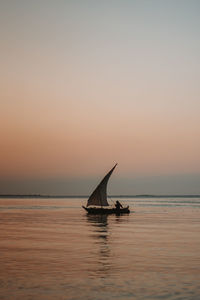 Scenic view of a fisherman in a fishing boat against sky during sunset