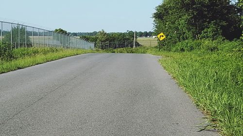 Road amidst trees against clear sky