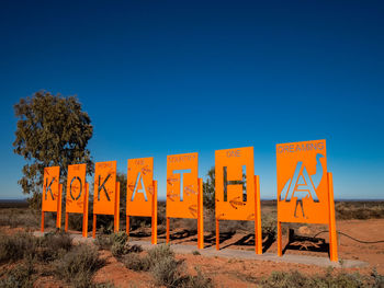 Information sign on field against clear blue sky