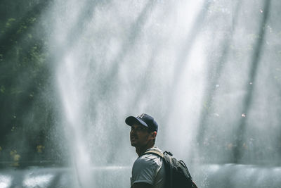 Portrait of man standing against waterfall