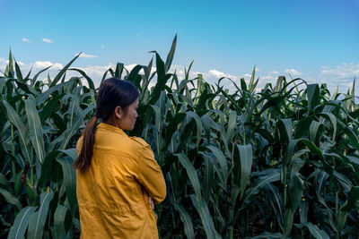 Rear view of woman standing in farm against sky